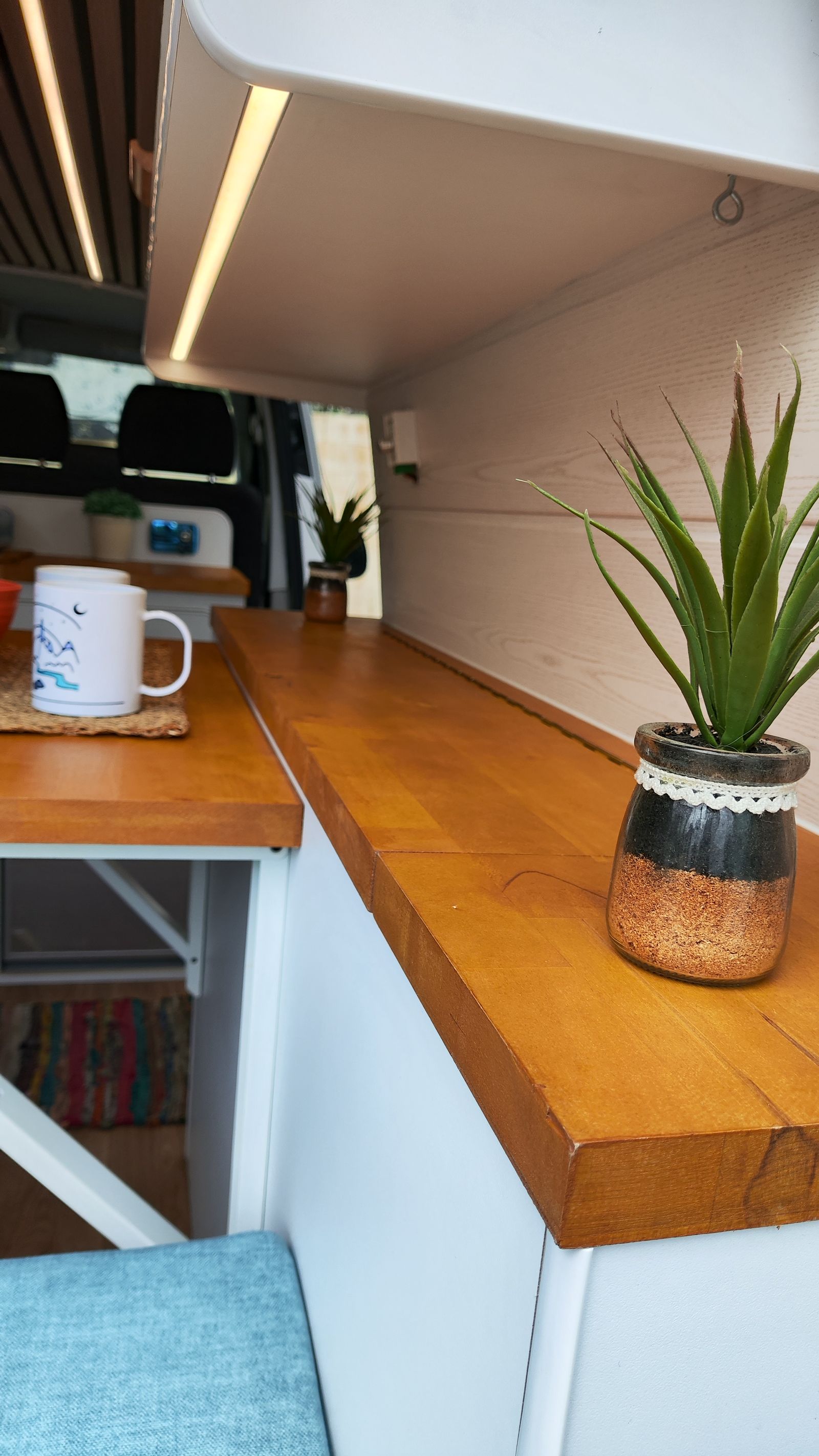 Detalle de la encimera de haya con una taza y una planta junto a la ventana.
